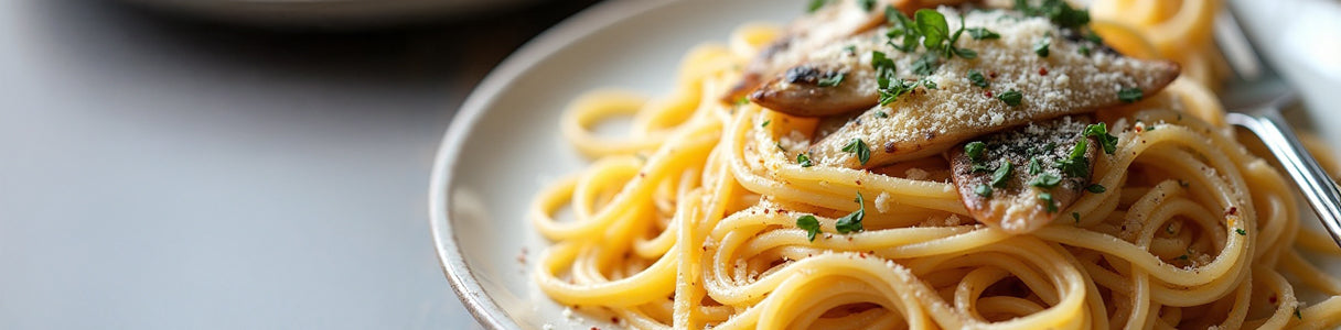 Close-up of spaghetti topped with sardine fillets, fresh herbs, and grated cheese on a white ceramic plate with a fork