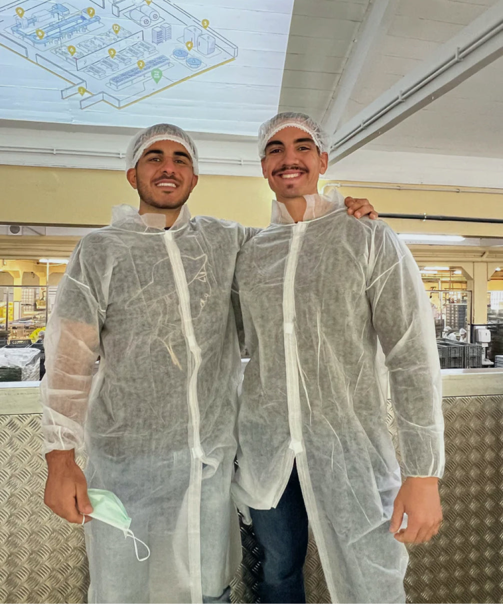 Two founders wearing protective gear and smiling inside a sardine production facility